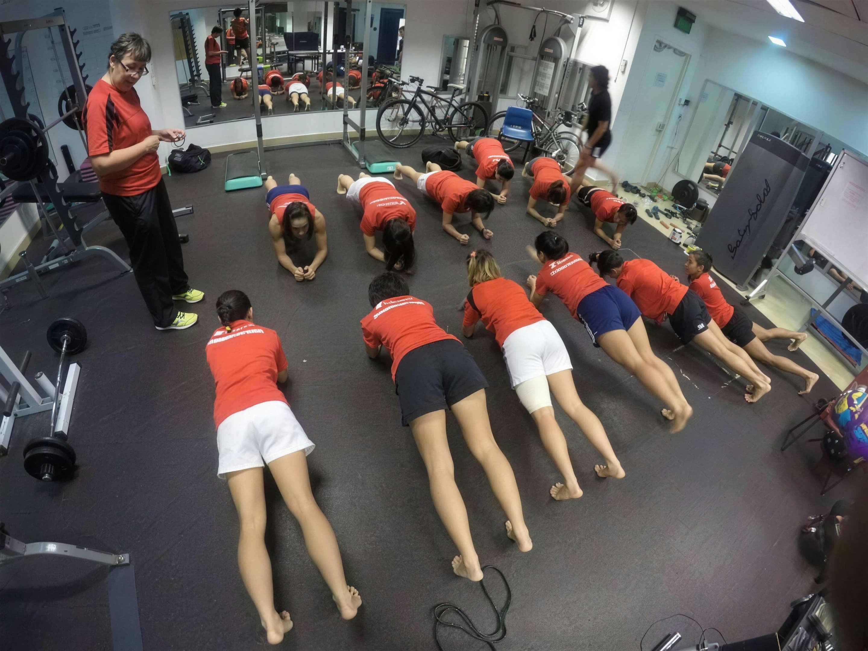 Joy Walter leading a women's rugby squad through a strength and conditioning session in a Singapore training gym